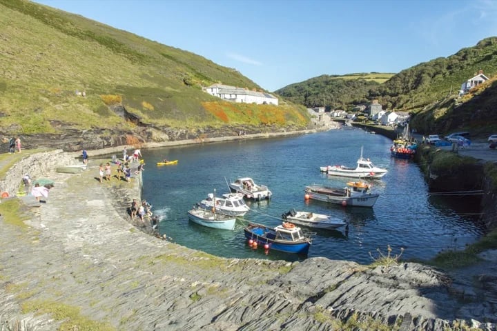 A small Cornish harbour in the sunshine with fishing boats floating in the deep blue water