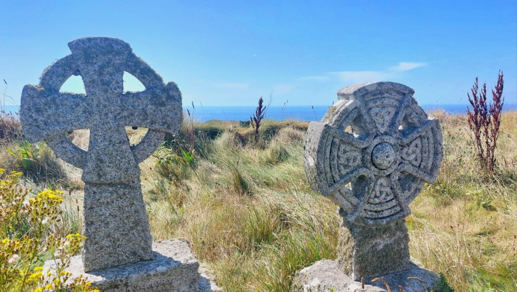 Celtic Cross gravestones in the sunshine overlooking blue sea