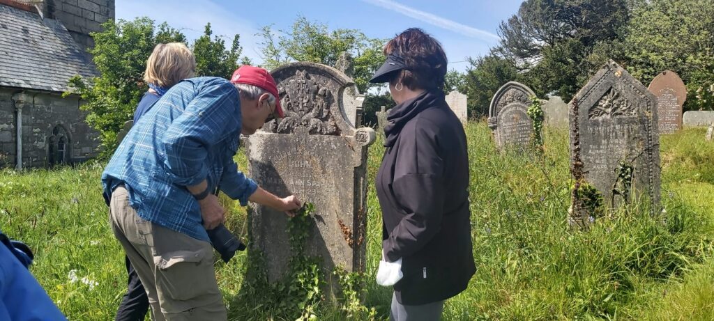 Tour guests in a graveyard examining a gravestone